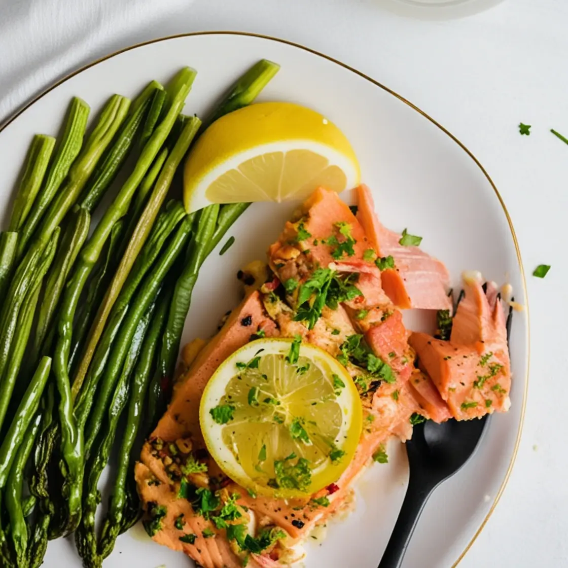 A beautifully plated dish featuring a tender, baked salmon fillet garnished with fresh parsley and a slice of lemon, accompanied by crisp green beans and a lemon wedge on the side.
